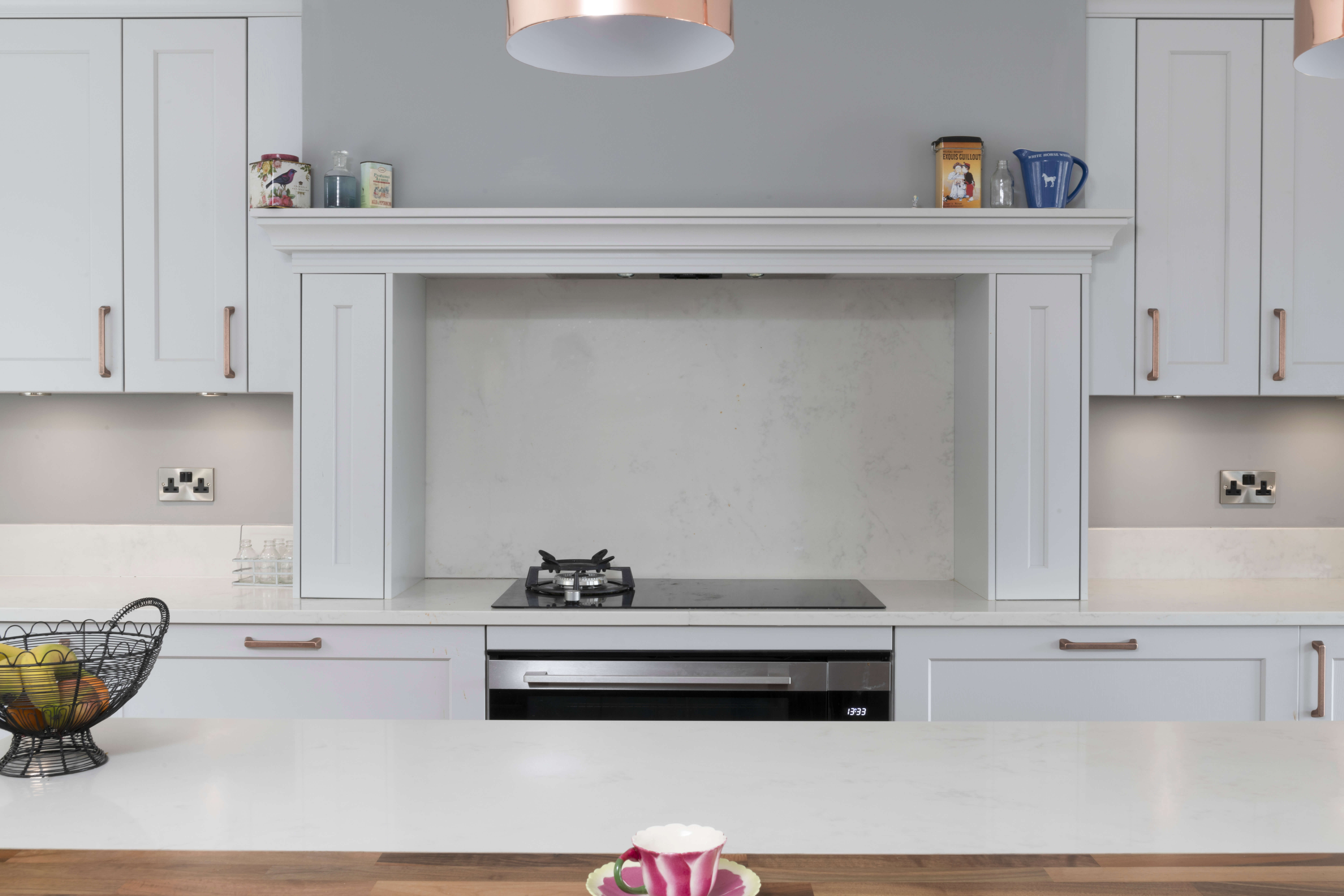 A pale grey kitchen is complemented by copper accessories