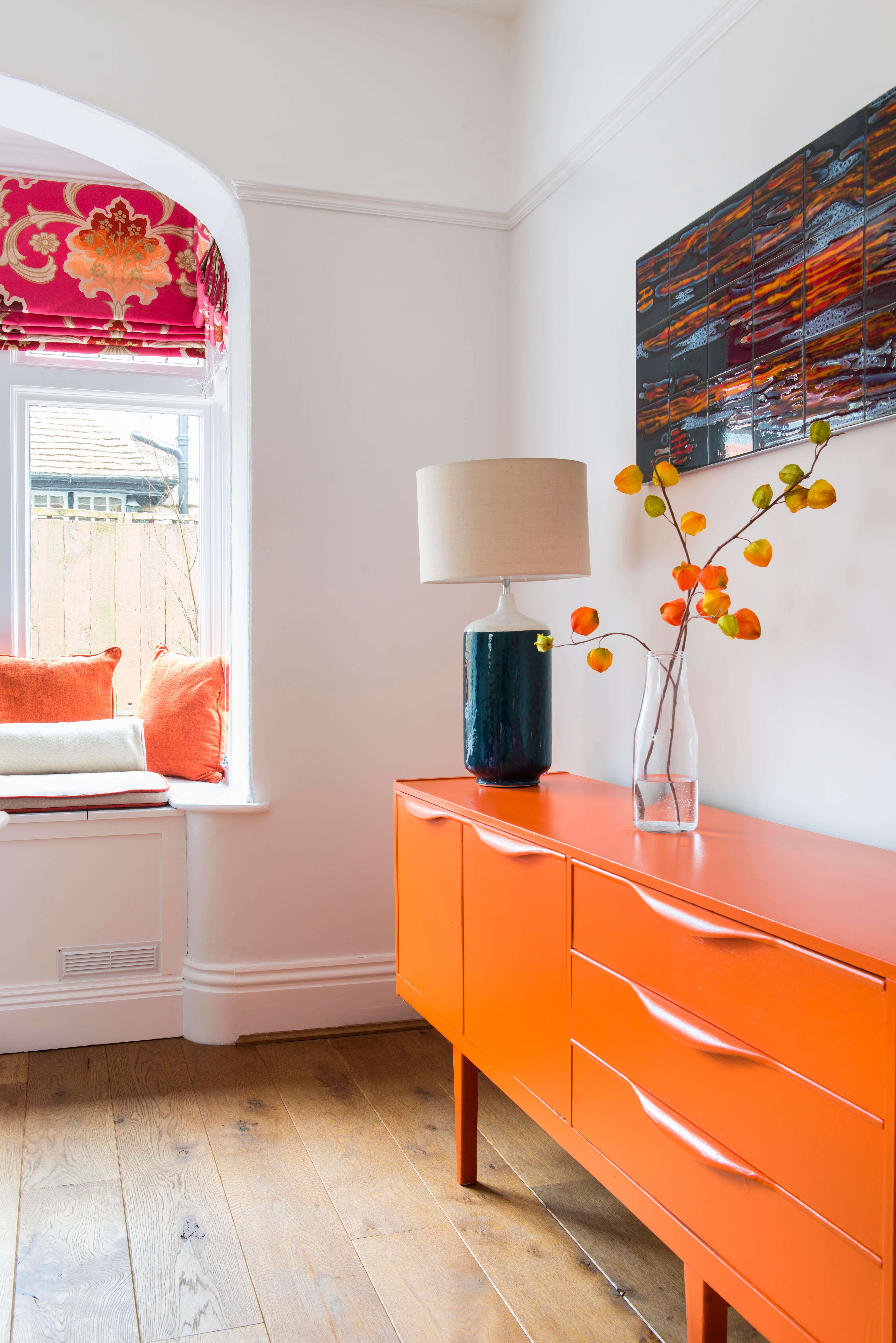 A G plan sideboard was painted a vibrant orange to complement the Designers' Guild blind