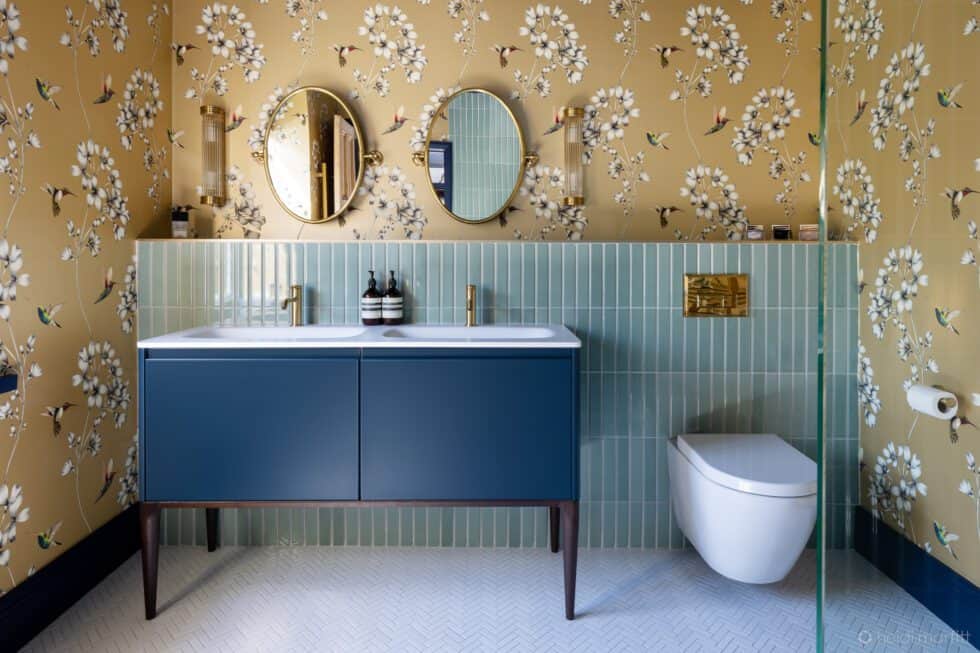 A generous navy vanity unit in this elegant shower room with mint green tiles, gold wallpaper and navy ceiling with brass taps and mirrors