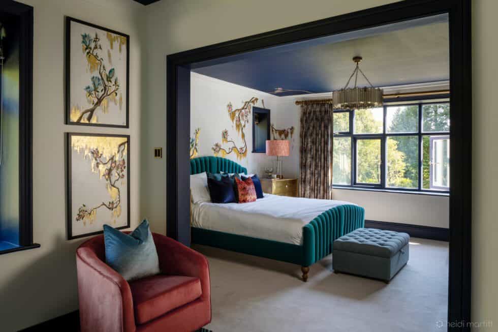Bespoke murals on the walls and ceiling of this master bedroom are complemented by the navy ceiling and the coral armchair, which tie in with the bedside lamps