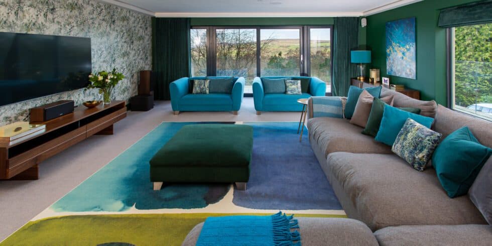 Turquoise snuggle chairs complement the bottle green walls and grey sofa in this family room