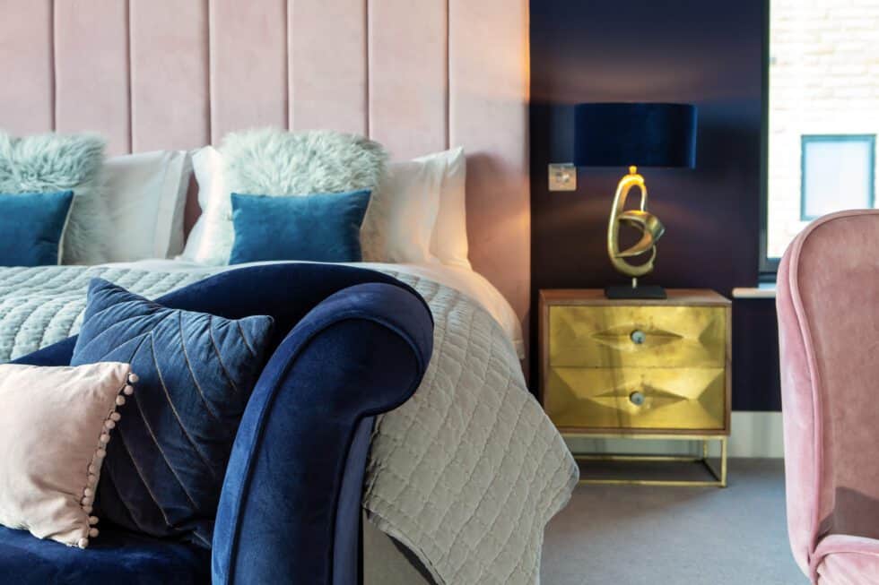 Navy walls and an oversized pink headboard add a sense of luxury to this master bedroom
