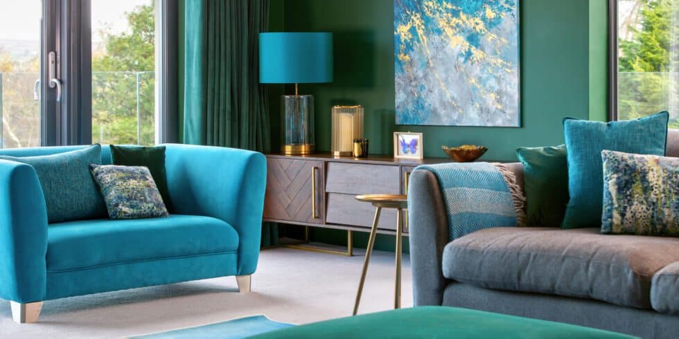 Turquoise snuggle chair and grey sofa complement the green walls in this family room