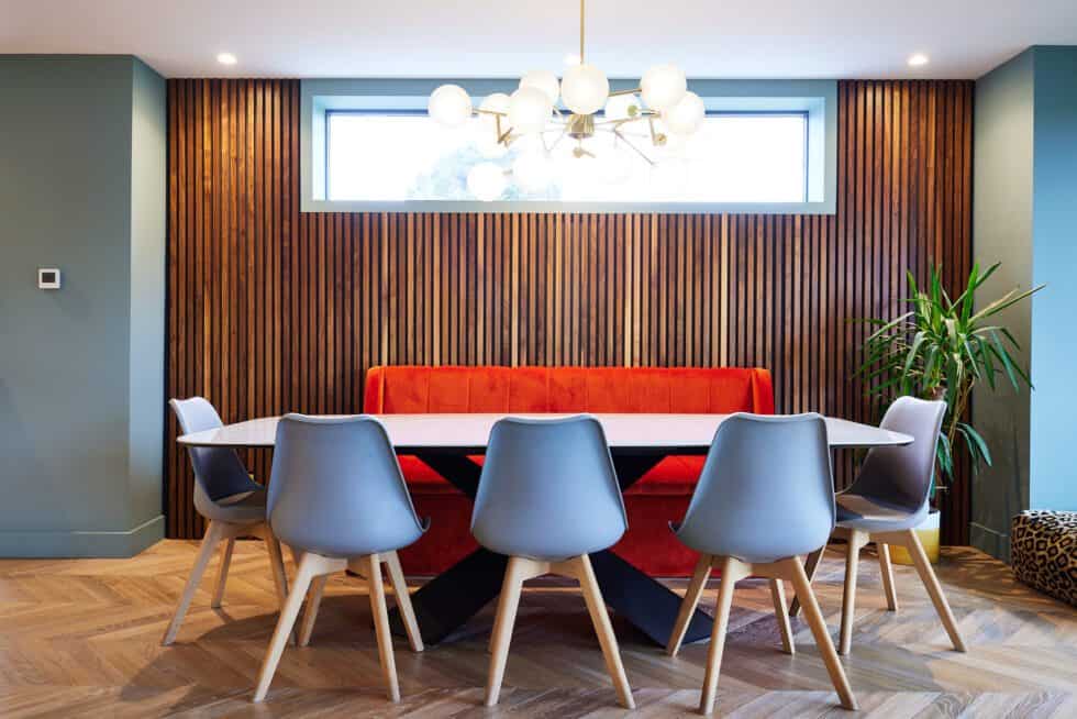 walnut panelling adds texture to this dining area where generous seating is provided by a bespoke orange banquette