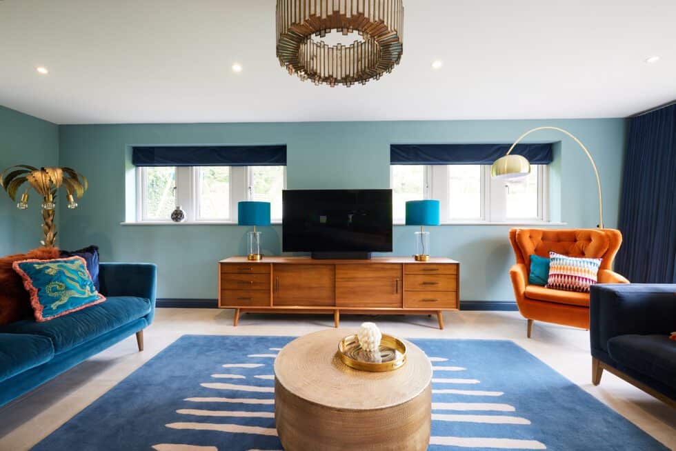 An orange armchair sits in a well lit family room with navy sofas, patterned cushions and bespoke navy blue curtains