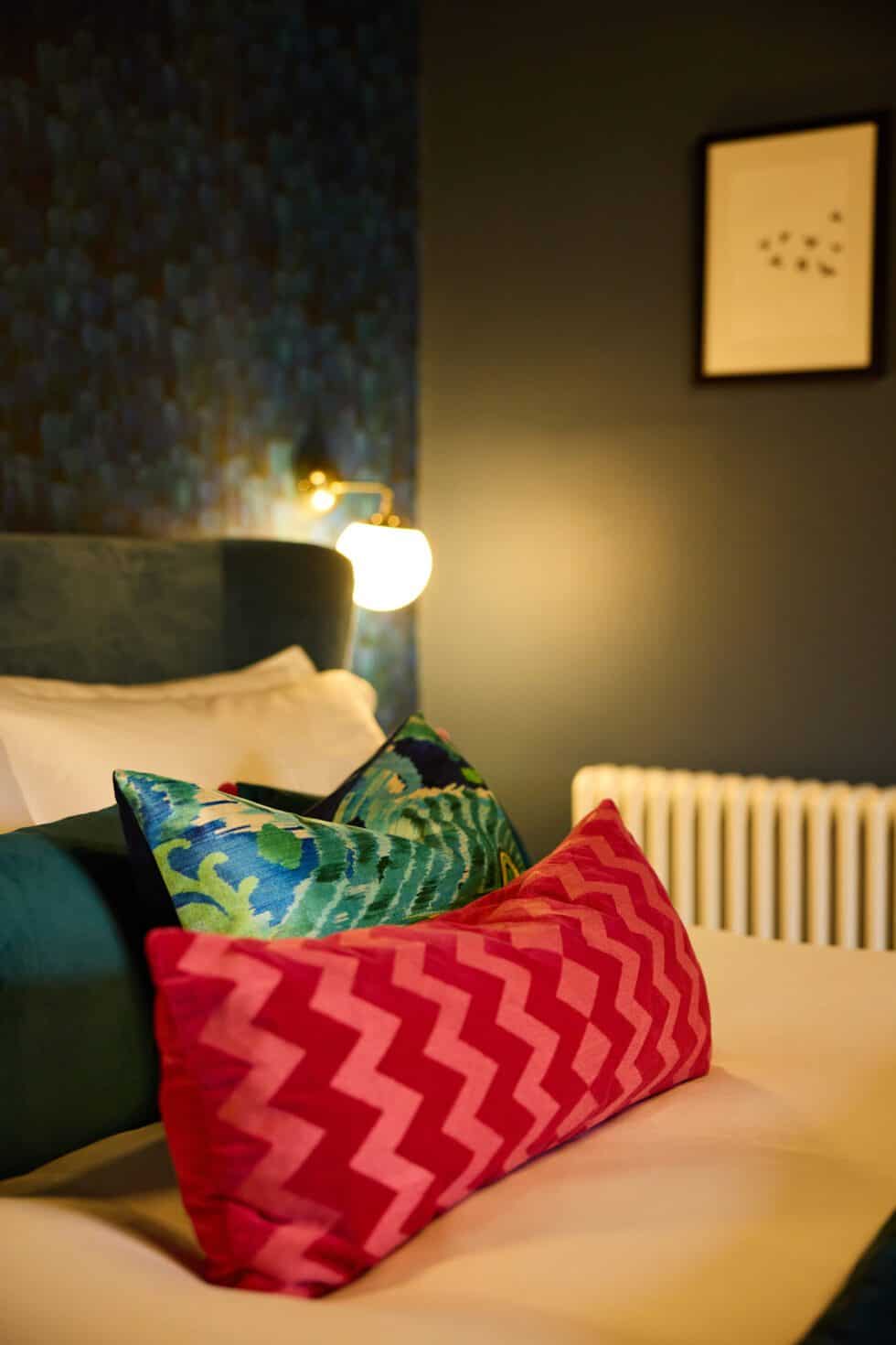 A striking pink chevron cushion adds interest to this master bedroom with inky navy walls