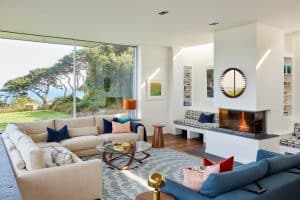 Contemporary sitting room with neutral L shaped sofa and navy and orange cushions, sitting on a blue patterned rug