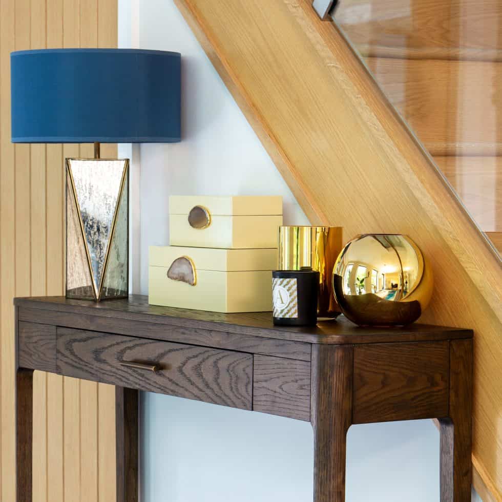 Adding beautiful scented candles, storage boxes to hide keys and a feature table lamp makes the most of this hallway